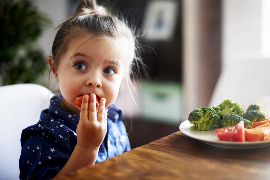 Servizio mensa scuola materna Pero: bambina mangia un piatto di verdure