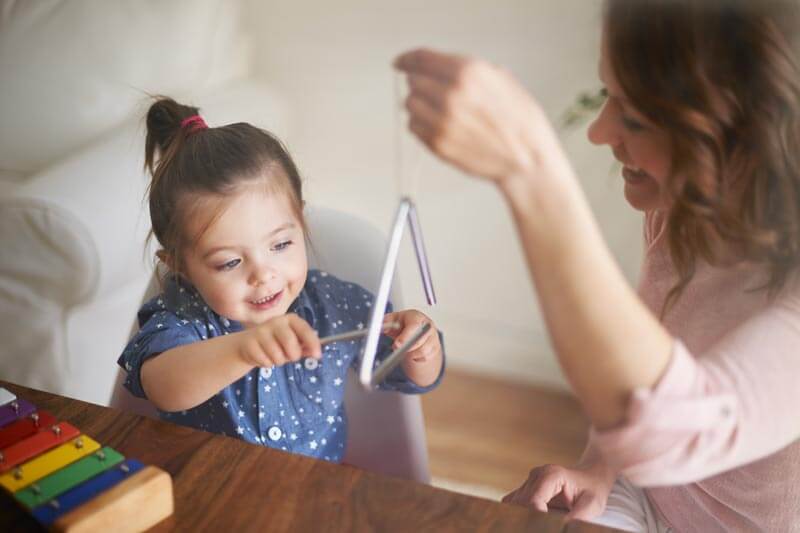 Scuola materna progetto musica: bambina suona il triangolo